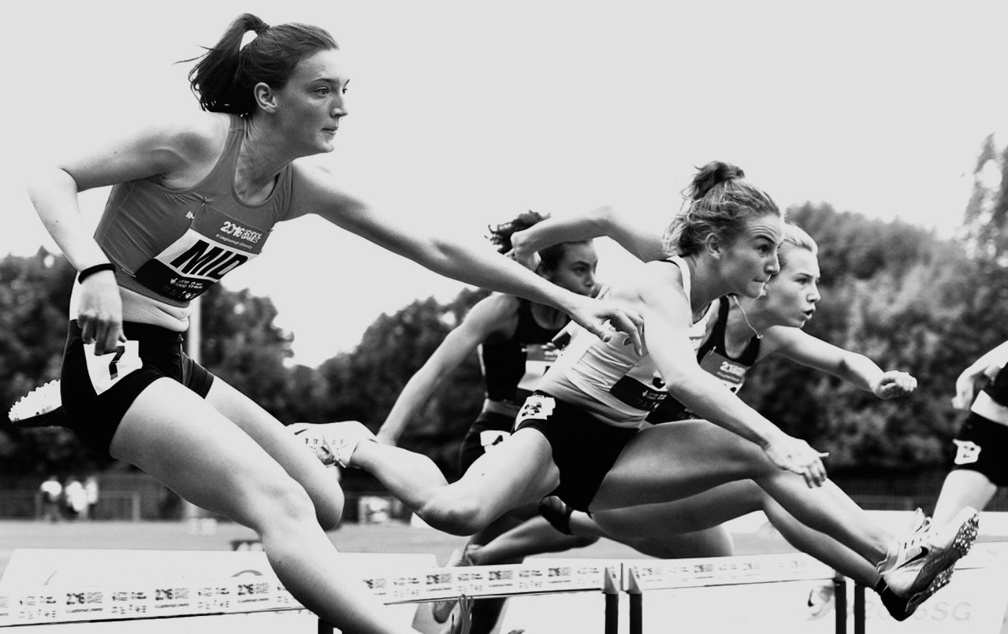 Pippa Earley clearing a hurdle mid-race, in black and white