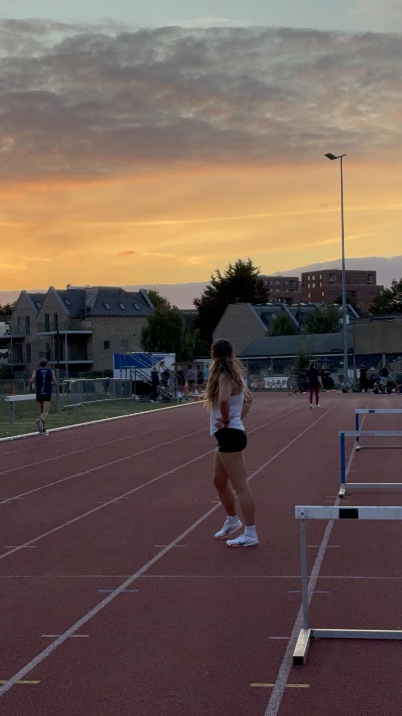 Pippa Earley alongside the hurdles on the track at sunset